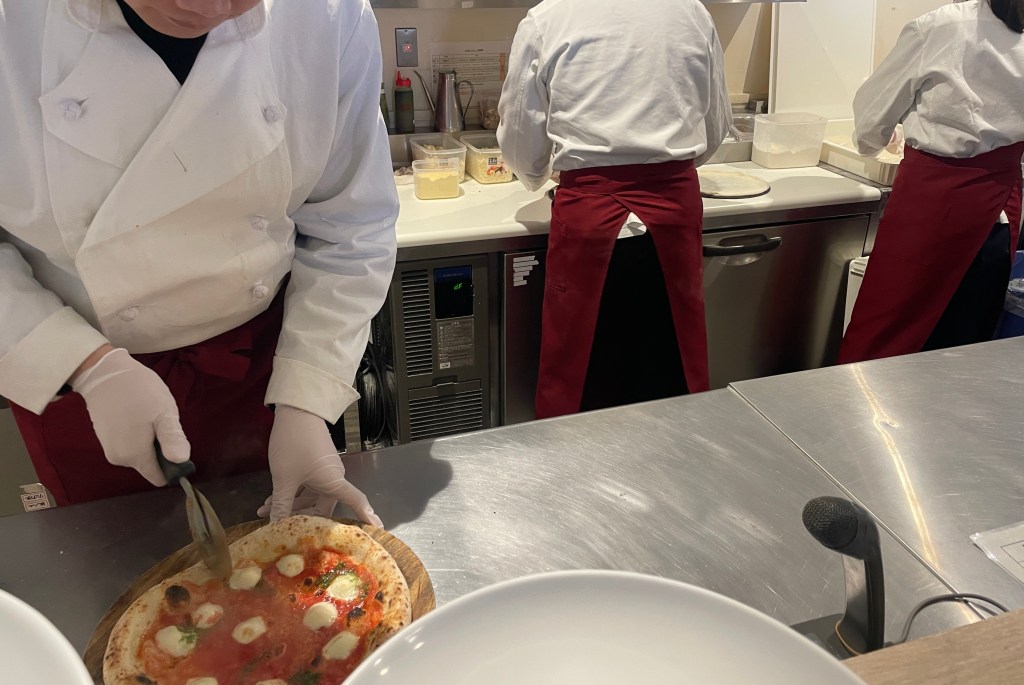 three kitchen staff preparing fresh pizza