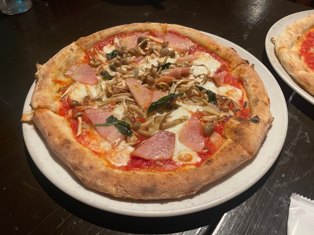 Ham and mushroom pizza on a white plate